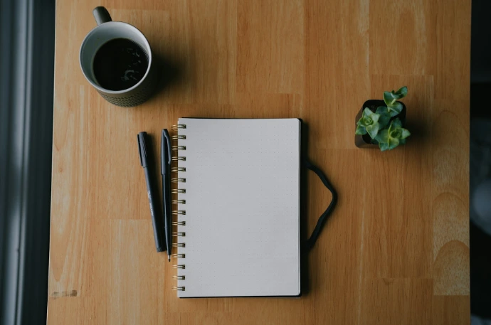 Notebook and coffee on a wooden table.